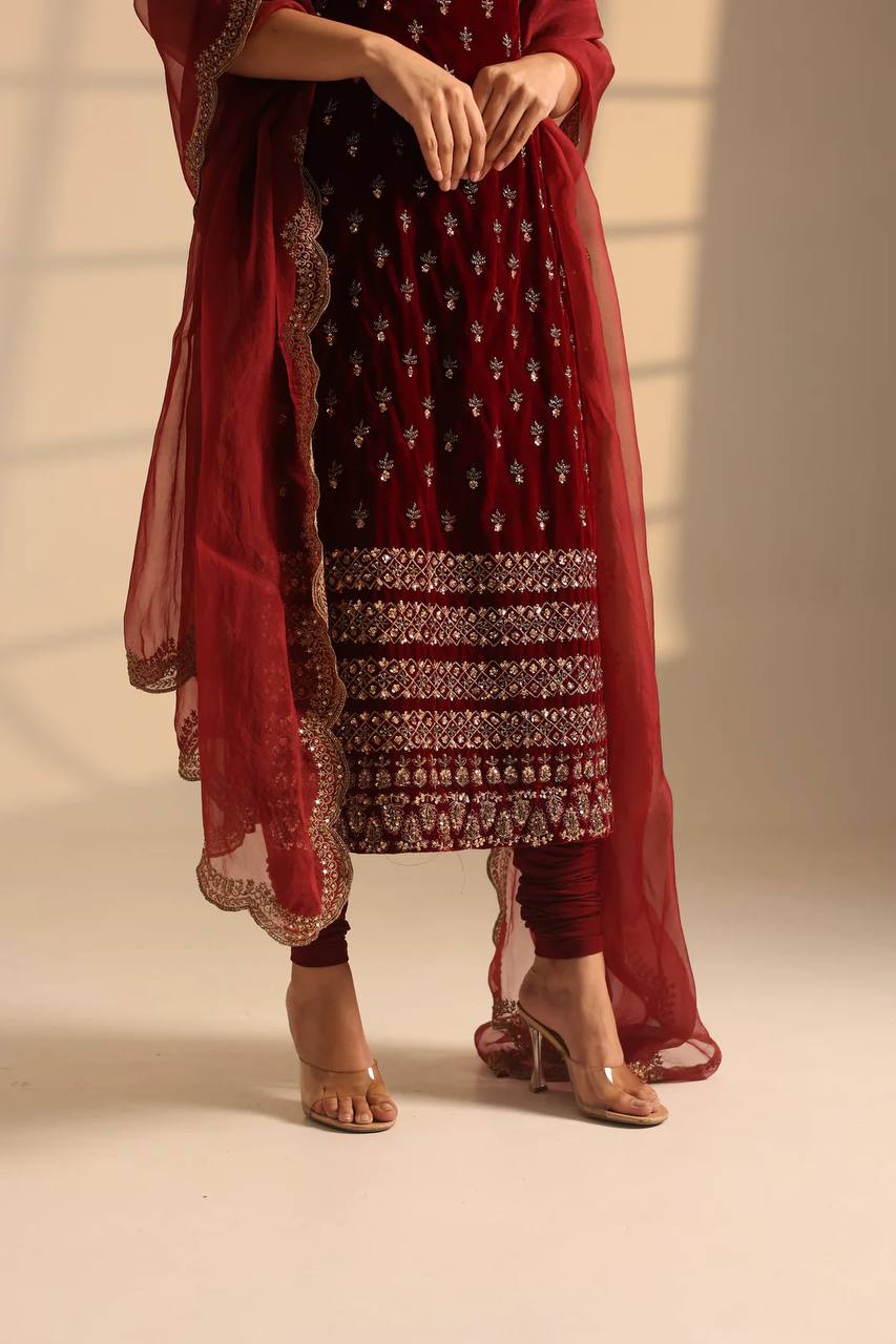 Red embroidered traditional outfit with a sheer dupatta on a neutral background