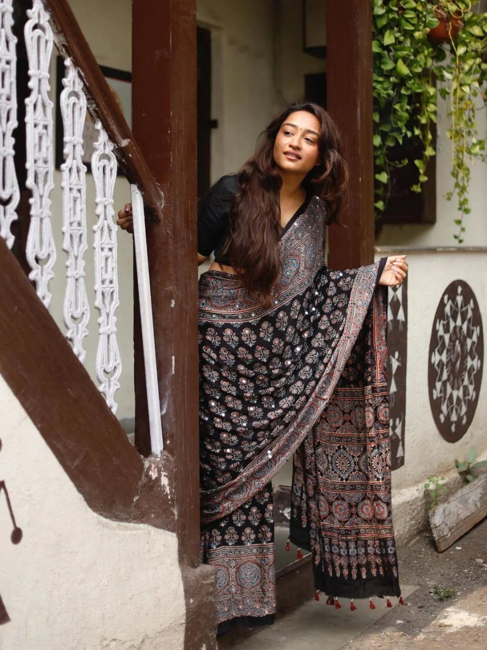 woman seated in black ajrakh modal silk saree with mirror work