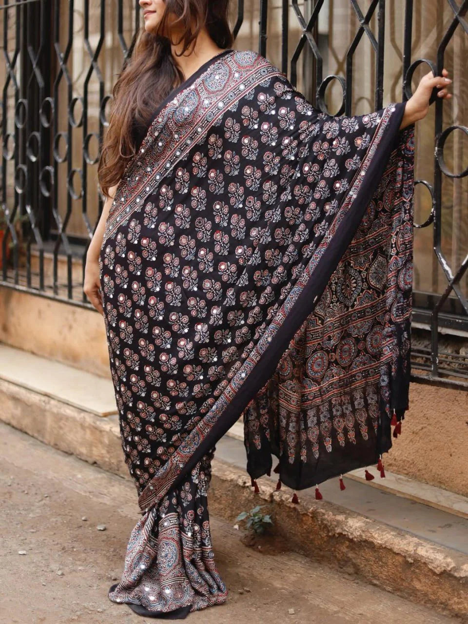 black ajrakh modal silk saree with tassel pallu on stairs