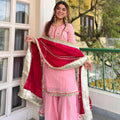 Side view of baby pink organza silk sharara set with lace border detail and maroon dupatta