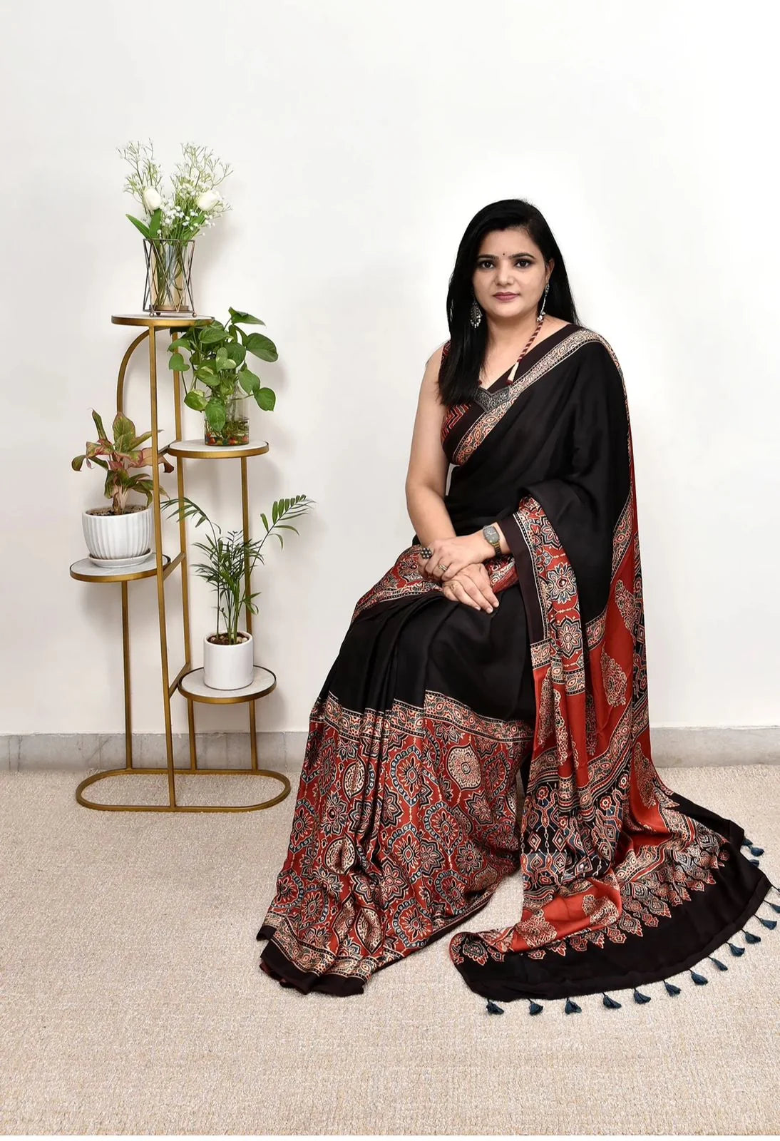 black ajrakh print saree in modal silk with rust ajrakh pallu seated pose