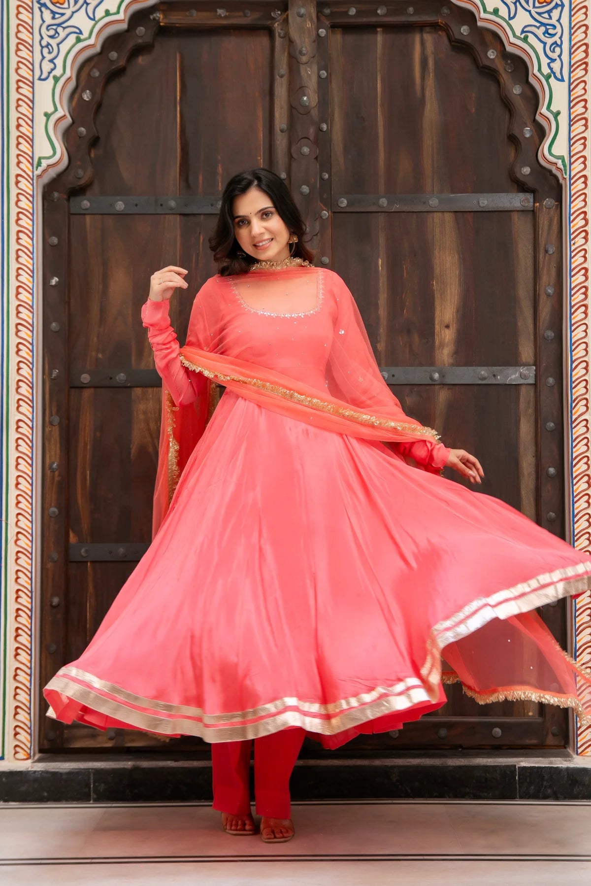 coral pink chinon anarkali twirl showing flared silhouette and gold border