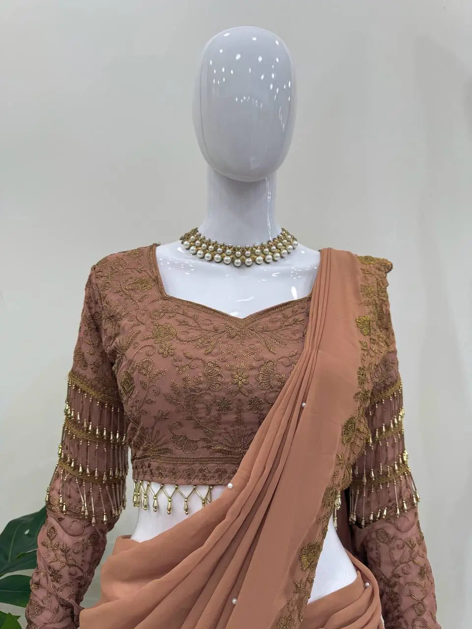 Elegant brown embroidered saree with gold detailing, pearl necklace, and matching blouse for women's ethnic wear