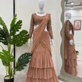 Elegant brown tiered lehenga with lace blouse and dupatta, displayed on mannequin with mirror reflection