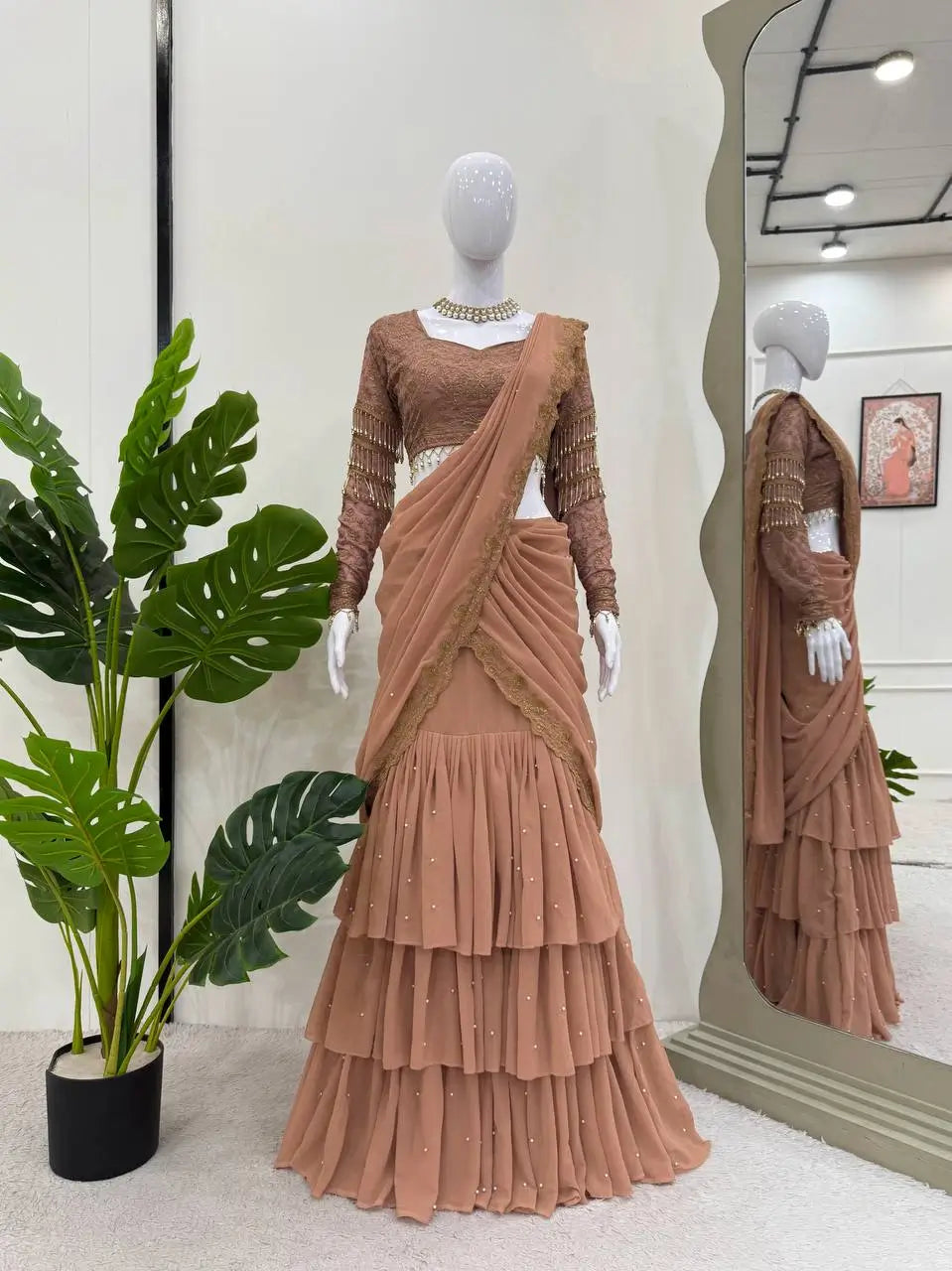Elegant brown tiered lehenga with lace blouse and dupatta, displayed on mannequin with mirror reflection