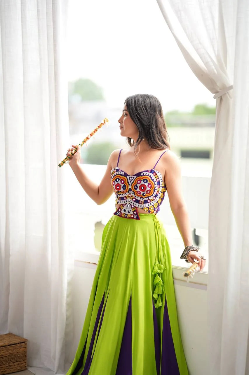 green purple garba lehenga with mirror work choli and dandiya sticks front pose