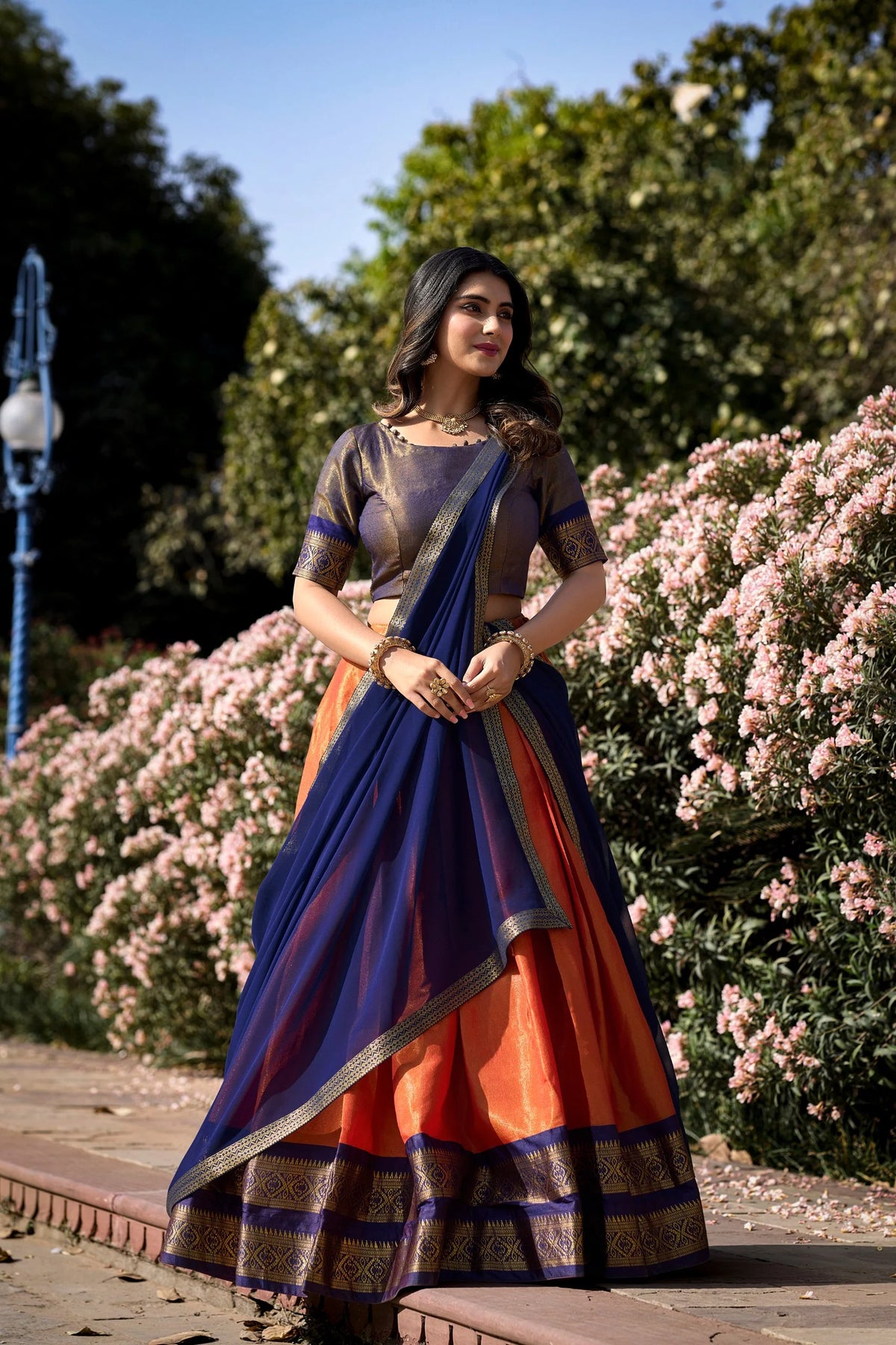 Dark green and red Kanchipuram half saree lehenga set standing full length with zari border