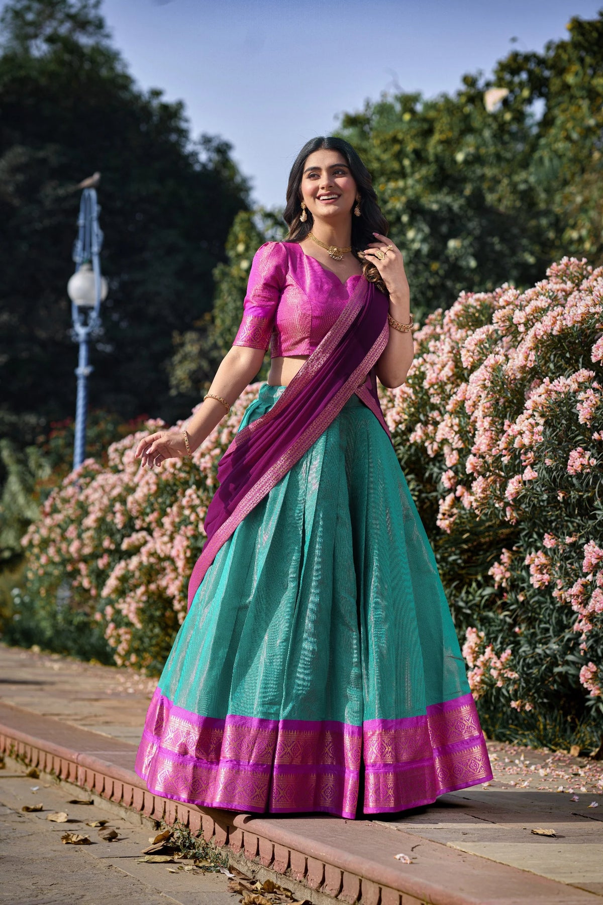 Purple and teal Kanchipuram half saree lehenga set outdoor garden view