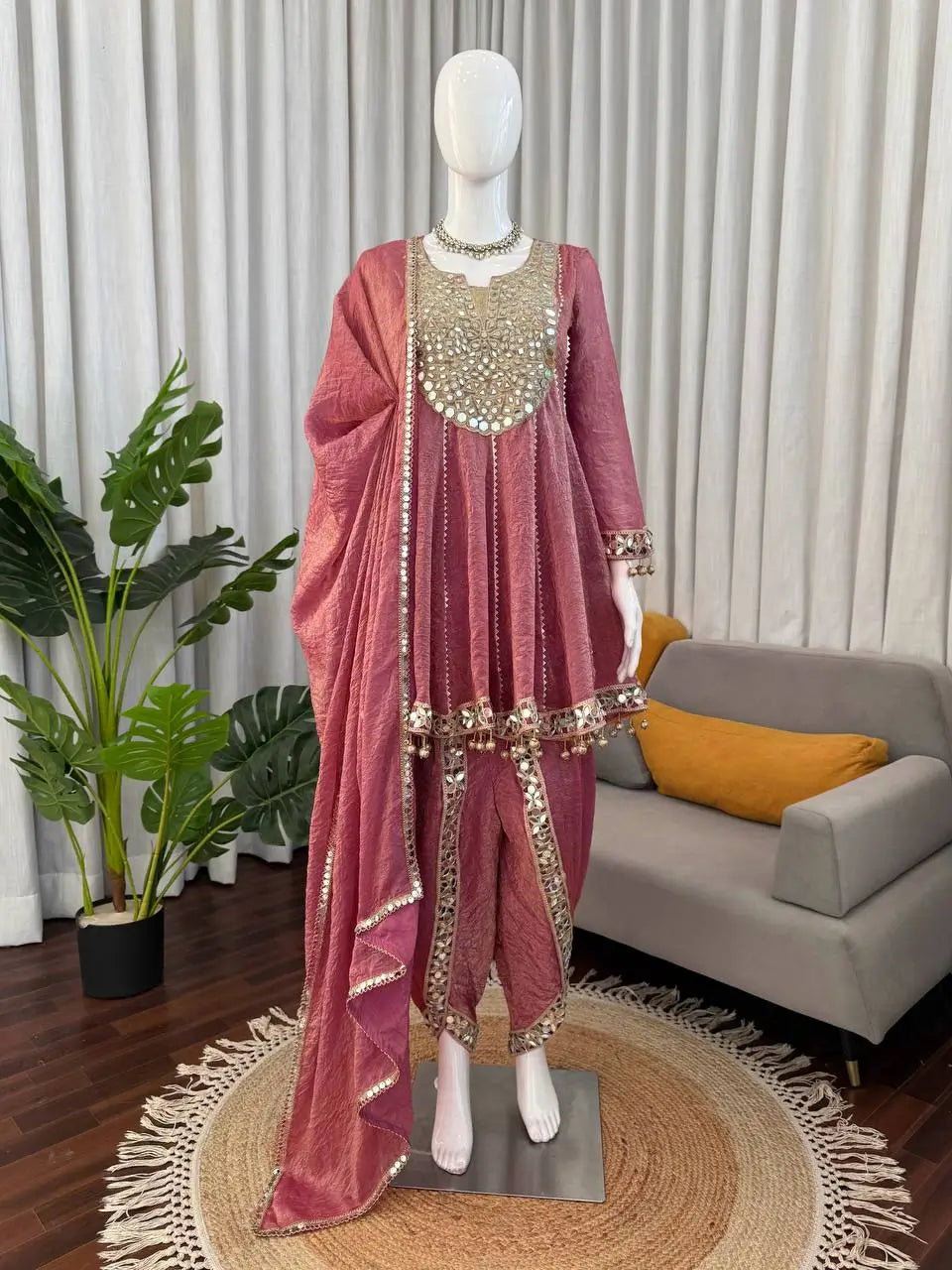 Pink ethnic sharara suit with gold mirror work and embellished dupatta, styled on mannequin for festive occasions