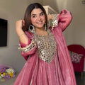 Pink velvet Anarkali gown with mirror work and gold embroidery, perfect for festive occasions