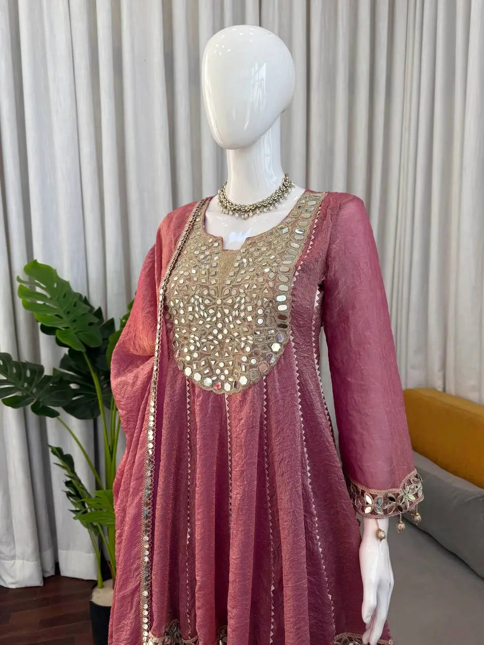 Pink Anarkali gown with mirror work and gold embroidery, displayed on mannequin for ethnic wear