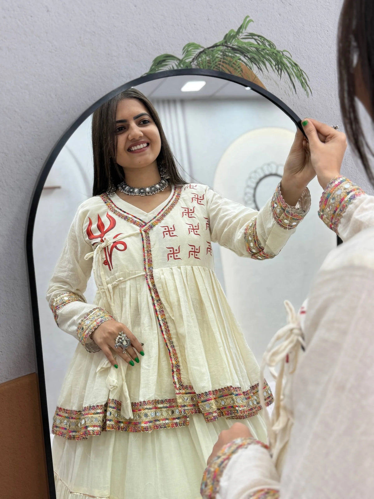 front view of off-white kediyu lehenga choli with swastik print and mirror lace border