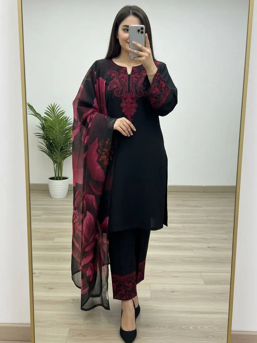 Woman taking a mirror selfie wearing a black outfit with red floral patterns.