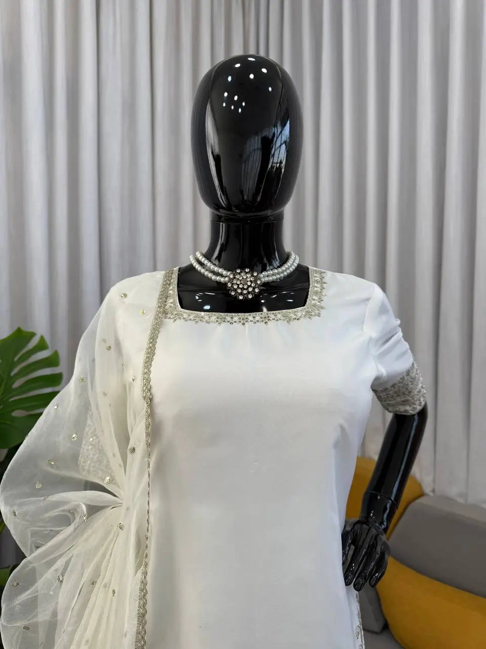 White saree with silver border on a mannequin against a neutral background