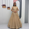 Woman in a beige traditional outfit standing in a minimalistic room with decorative elements.