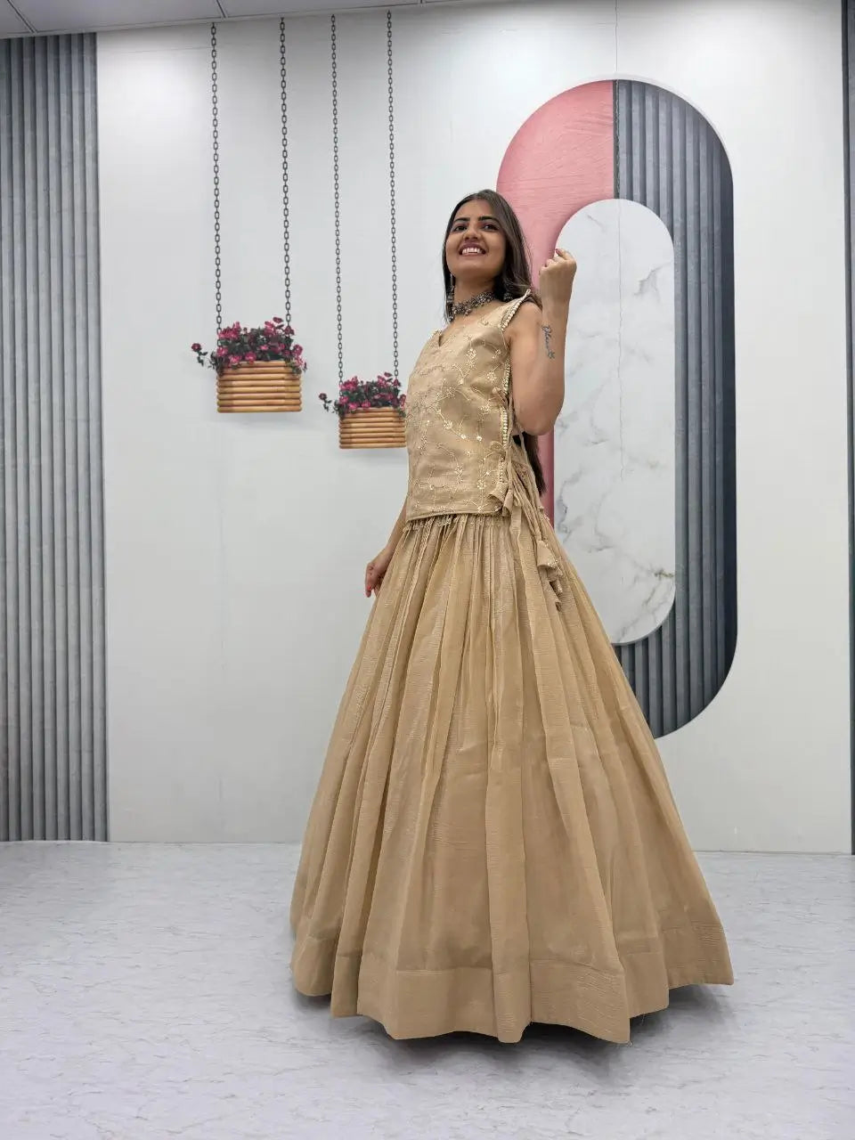 Woman in a beige dress standing in a room with decorative elements.
