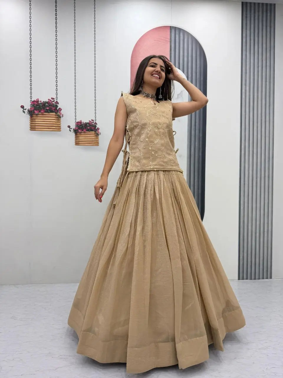 Woman wearing a beige traditional outfit standing in a room with decorative elements.