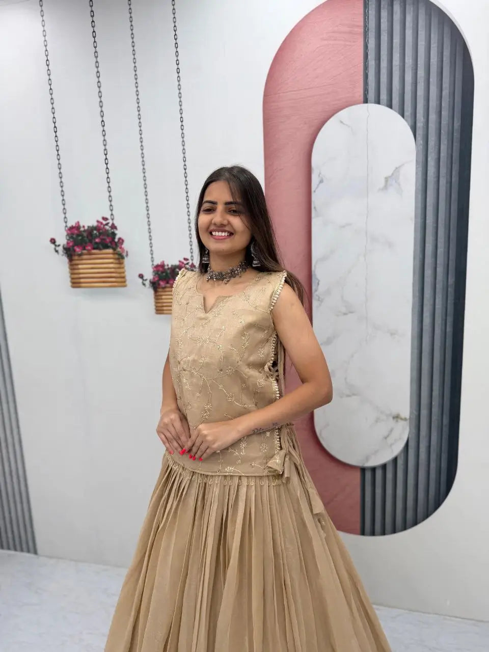 Woman in a beige dress standing in a room with decorative elements.