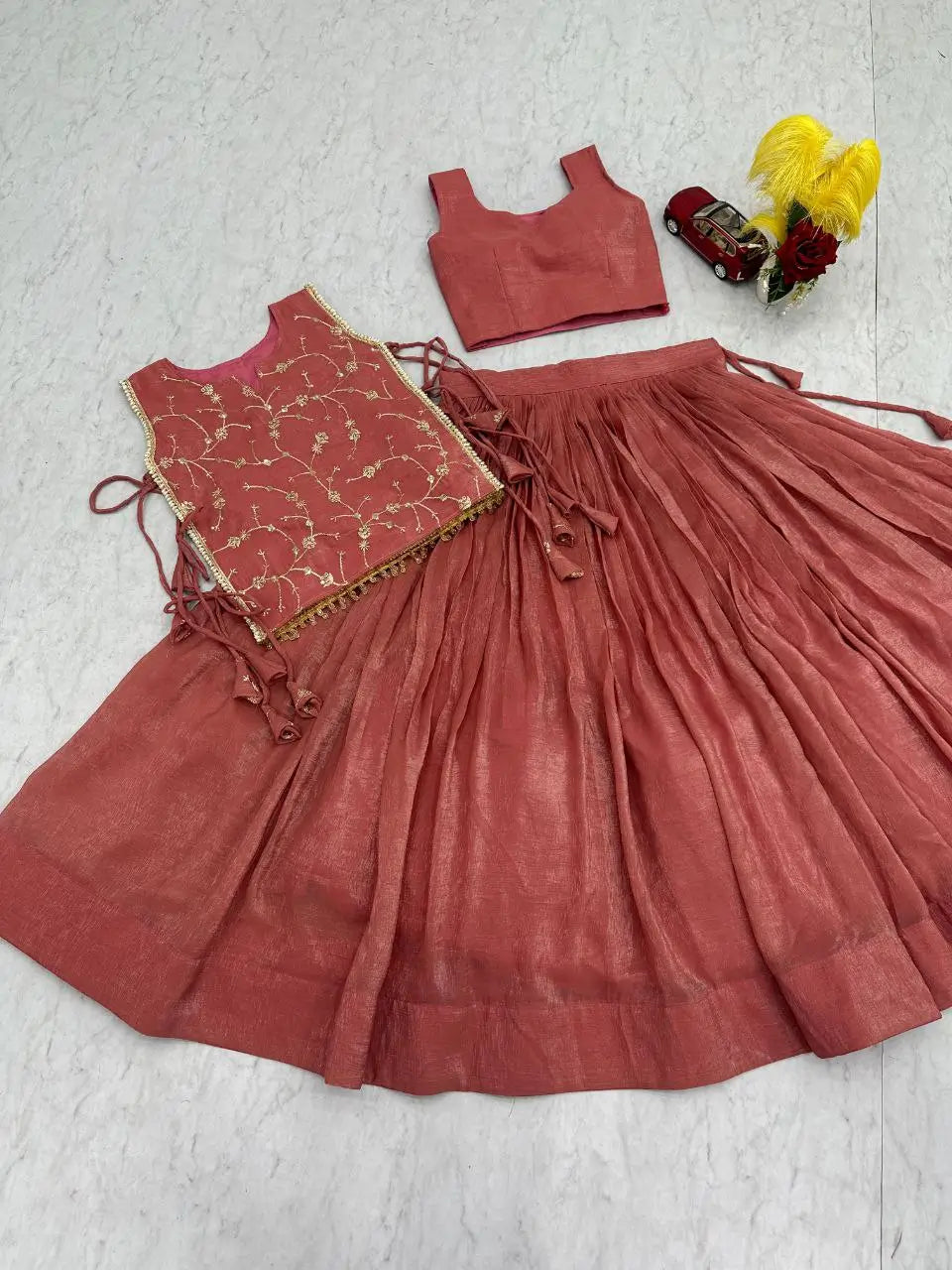 Red traditional outfit with a top and skirt on a textured white surface.