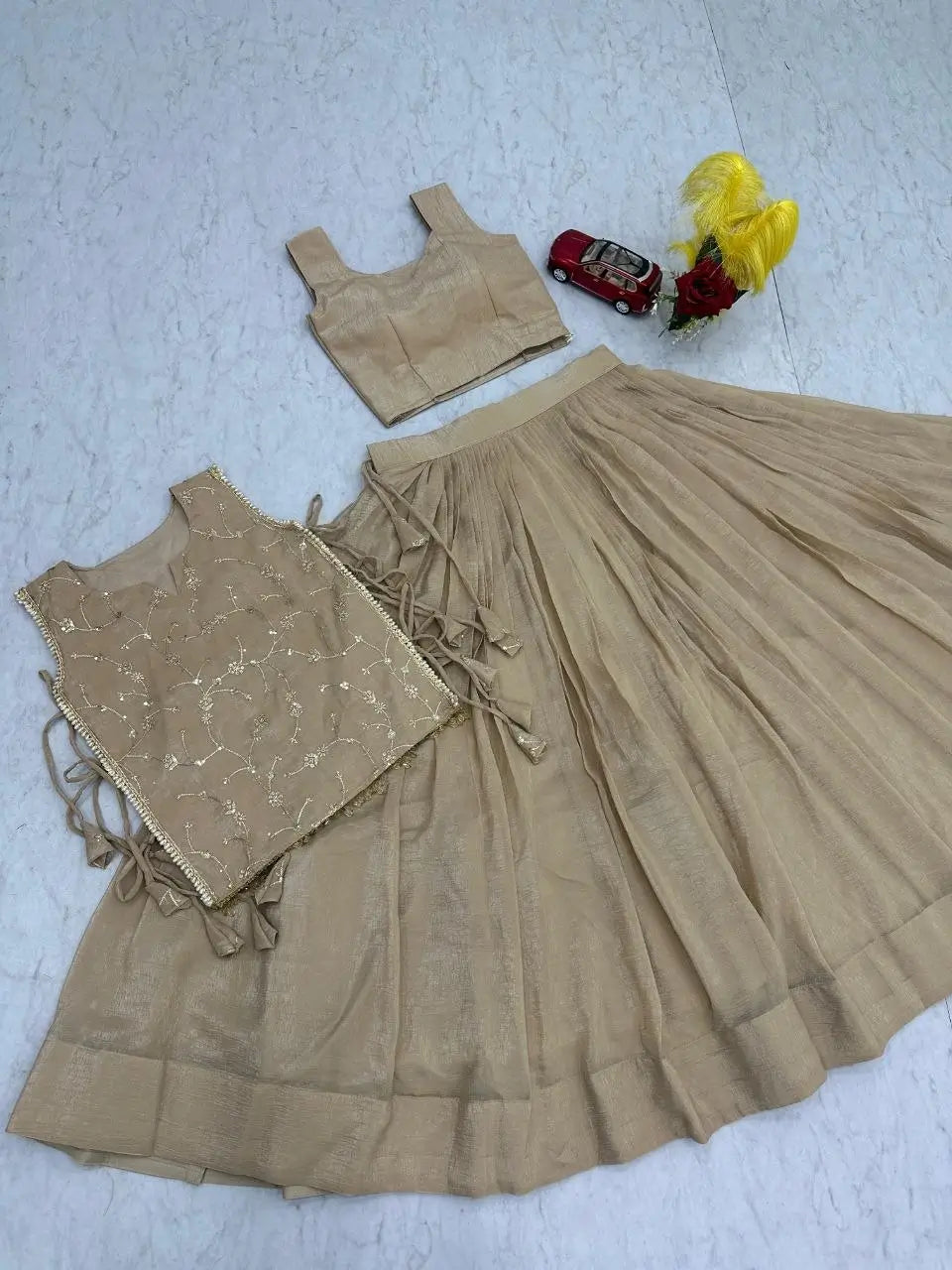 Beige top and skirt set on a light blue surface with small toys.