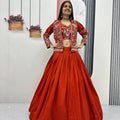 Woman in a red traditional outfit with a matching jacket, standing indoors.