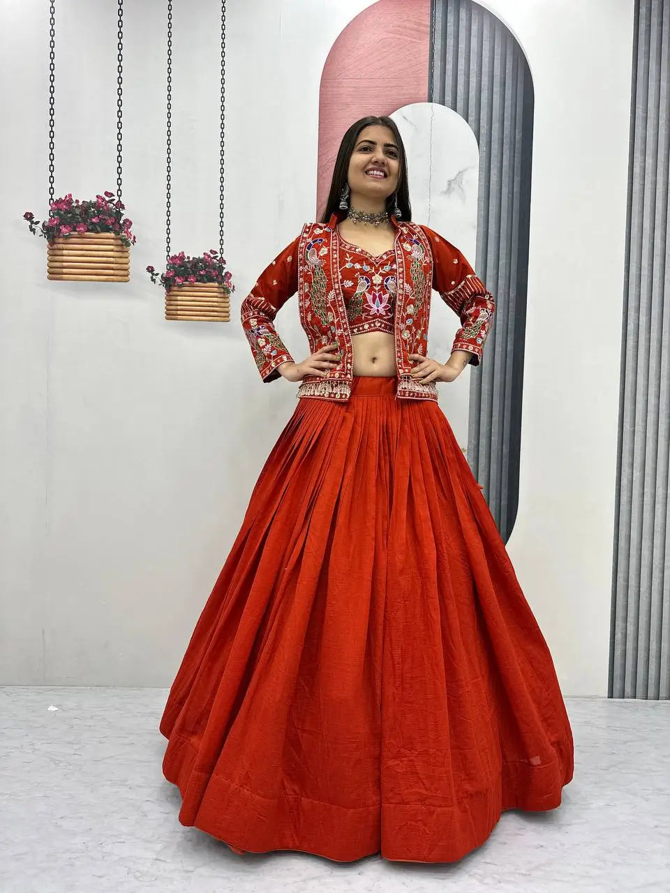 Woman in a red traditional outfit with a matching jacket, standing indoors.