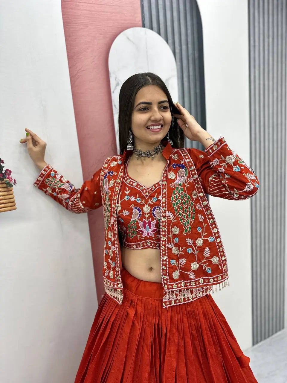 Woman in a red embroidered traditional outfit posing in front of a mirror.