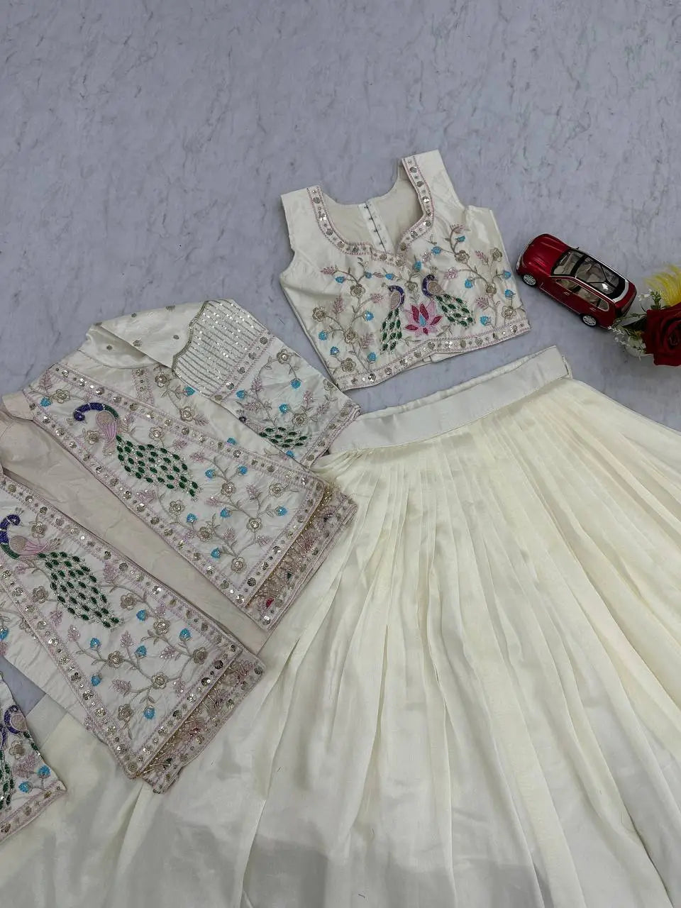 Embroidered traditional outfit with a blouse and skirt on a textured surface.