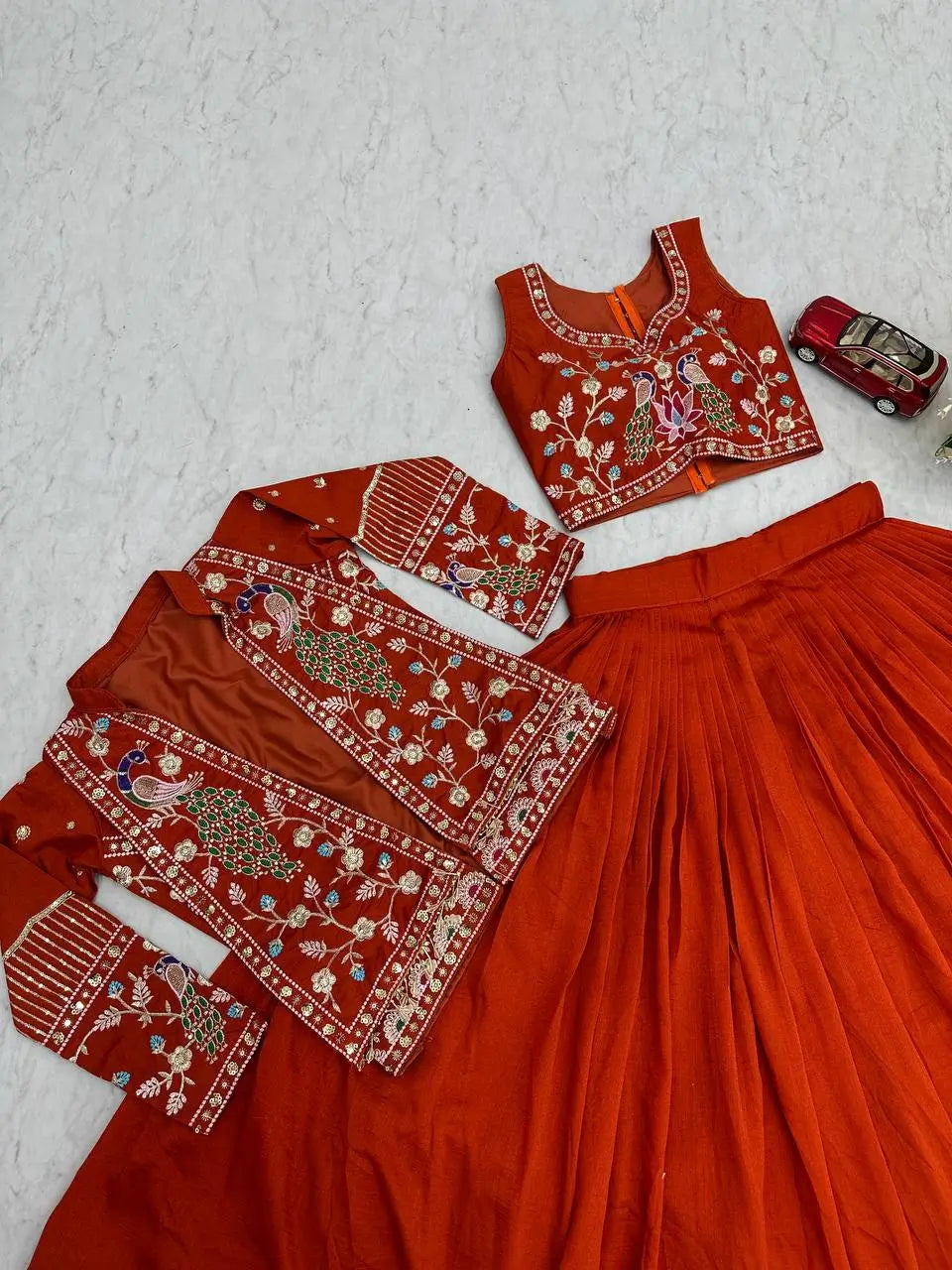 Red traditional outfit with intricate embroidery on a textured white surface