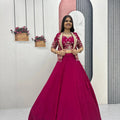 Woman in a pink traditional outfit standing in a room with decorative elements.