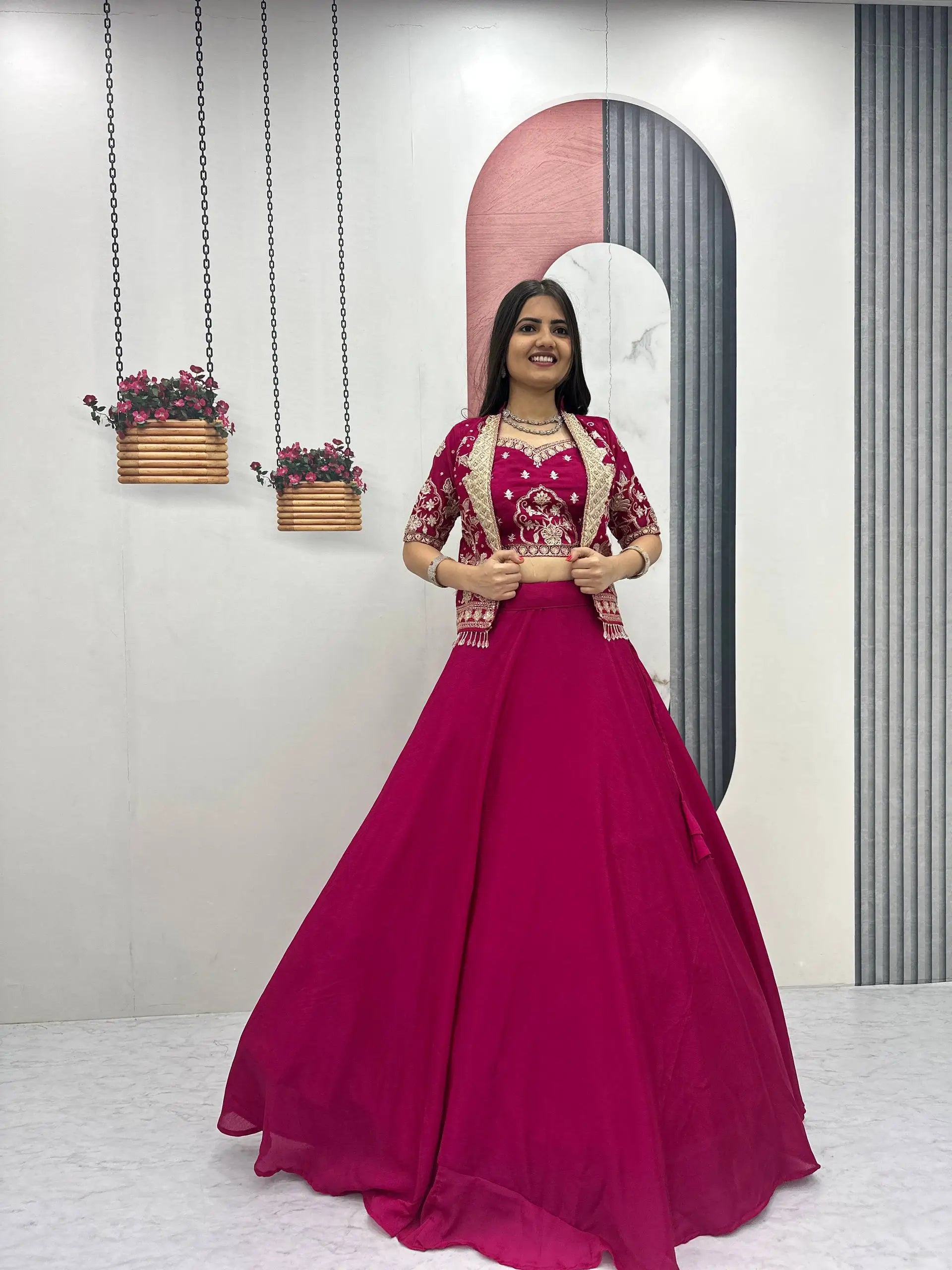 Woman in a pink traditional outfit standing in a room with decorative elements.