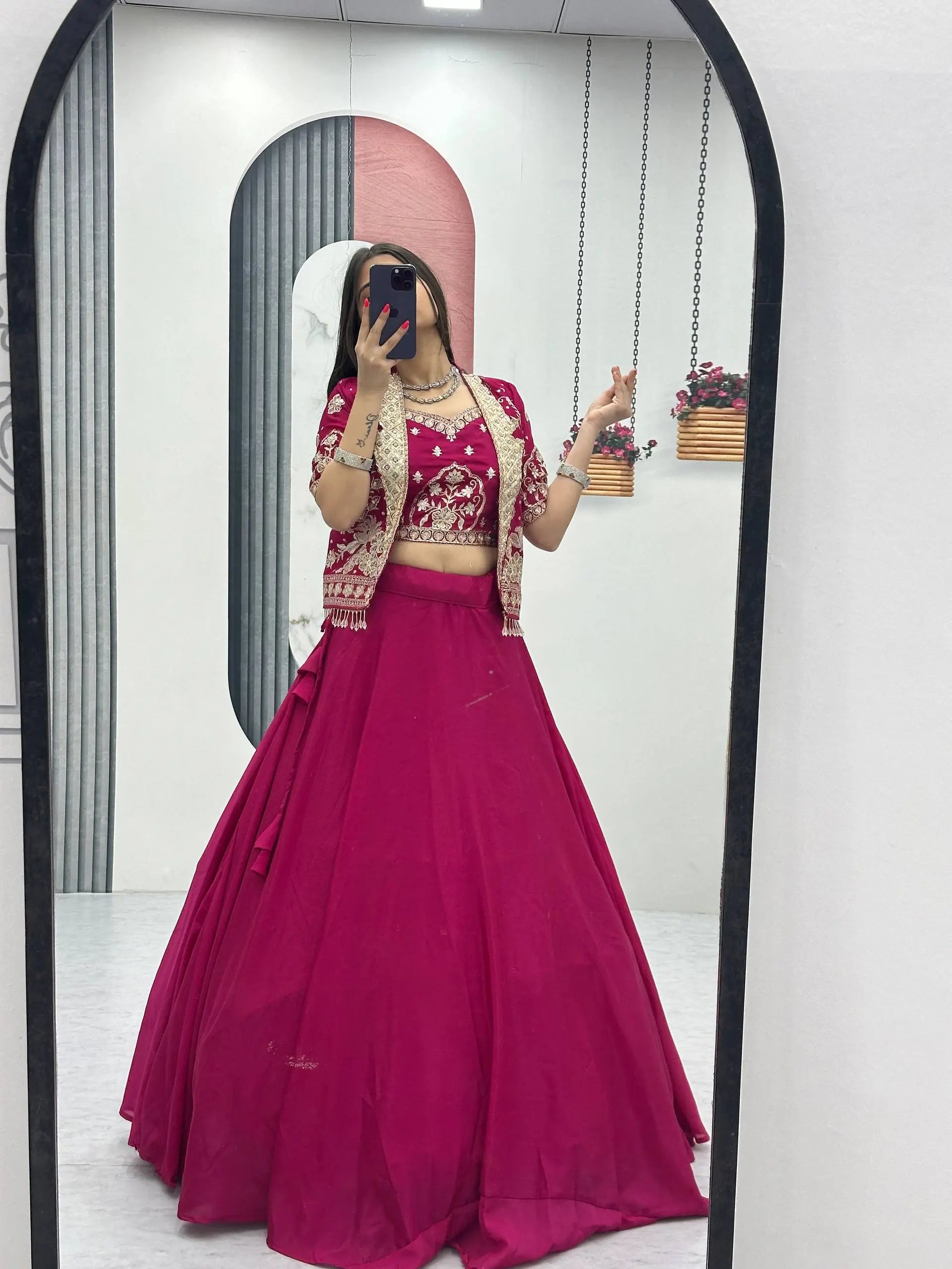 Person wearing a pink traditional outfit with a matching dupatta, standing in front of a mirror.