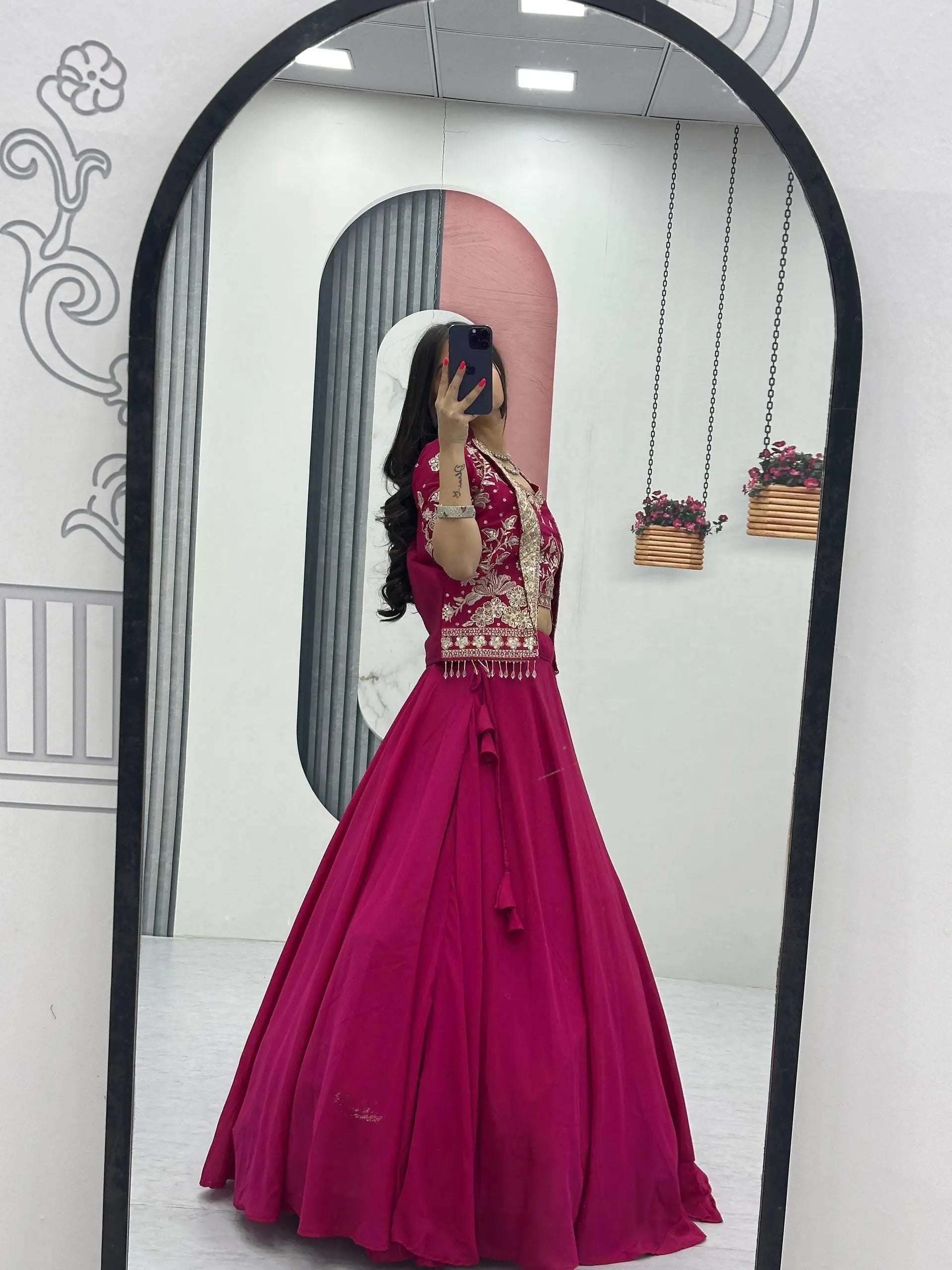 Person wearing a pink traditional outfit with gold details in front of a mirror.