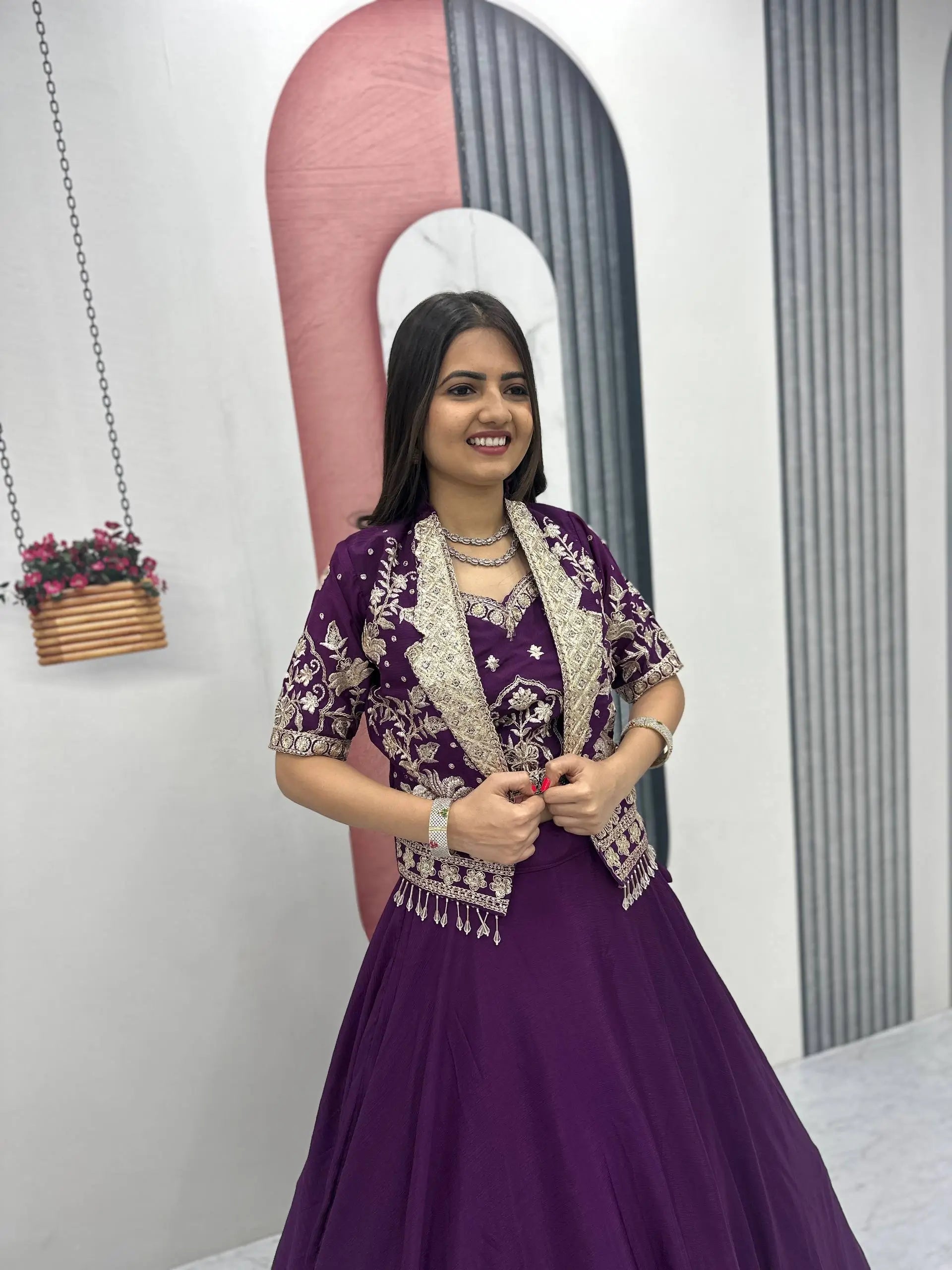 Woman in a purple traditional outfit standing in front of a decorative archway.