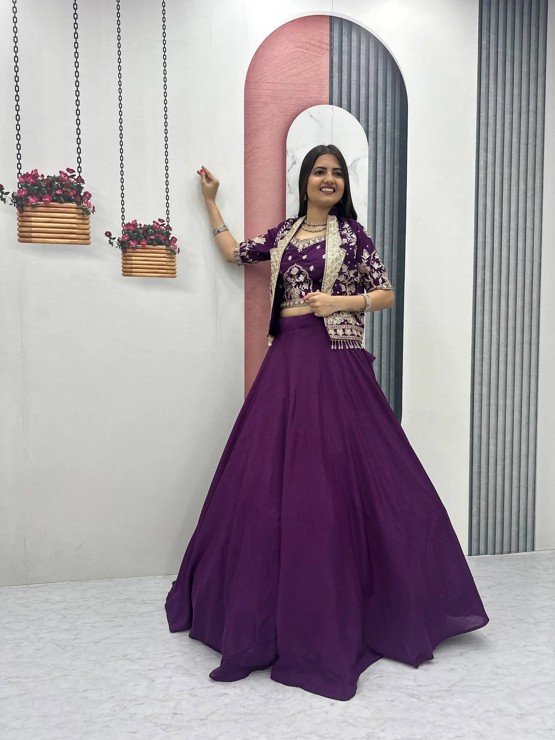 Woman in a purple traditional outfit standing in front of a decorative archway.