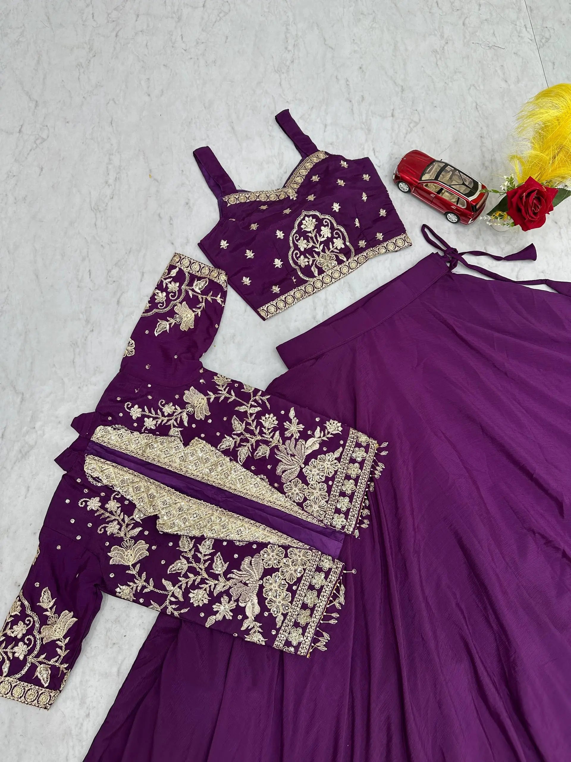 Purple embroidered traditional outfit with a car model and flowers on a light gray background
