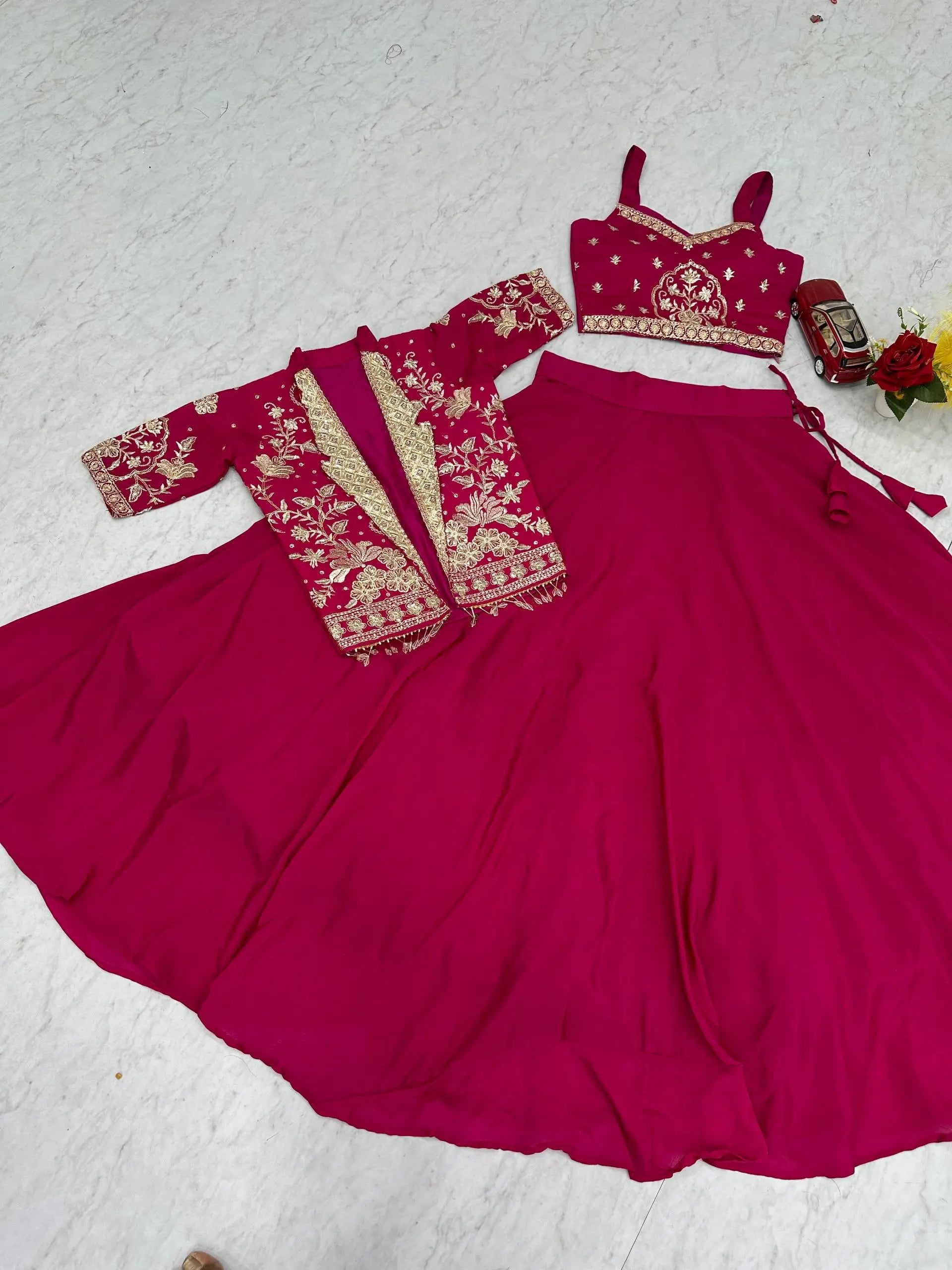 Pink traditional outfit with embroidered blouse on a light gray background