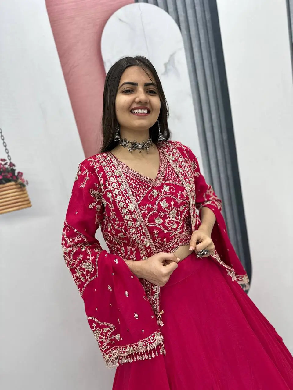 Woman in a red traditional outfit with intricate patterns indoors.