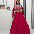 Woman in a red traditional outfit standing in front of a mirror with decorative plants in the background.