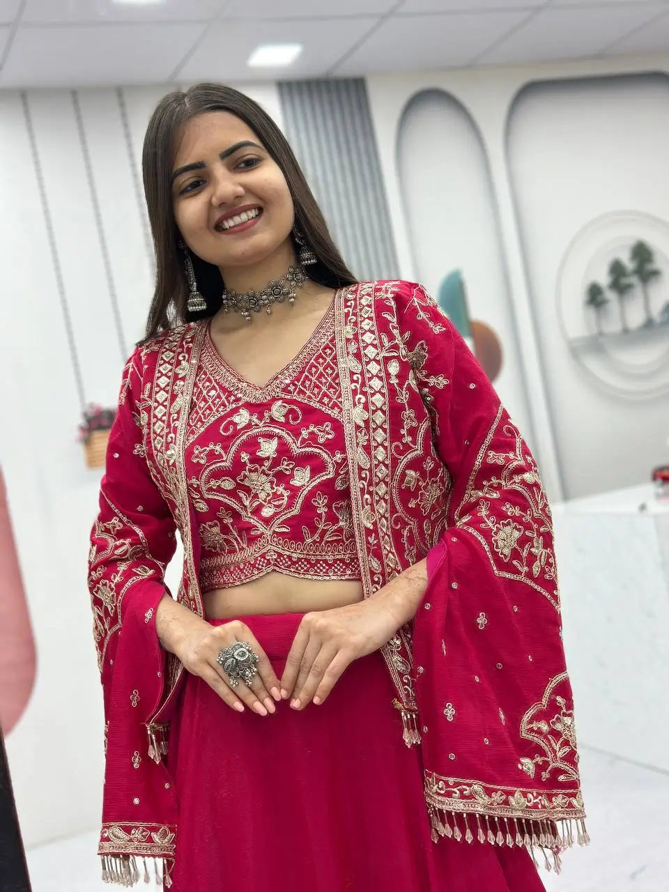 Woman in a red traditional outfit with gold embroidery indoors.