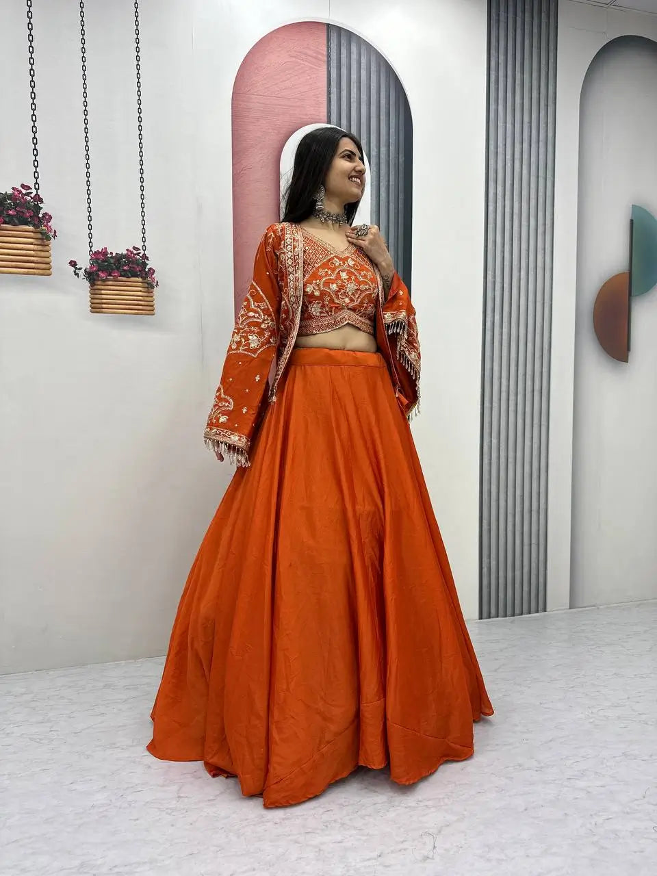 Woman in an orange traditional outfit standing in a modern interior setting.