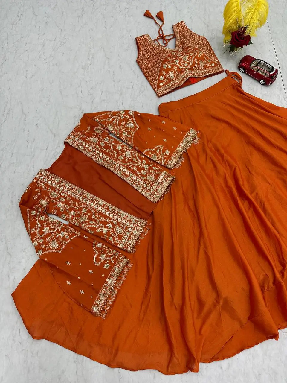 Orange traditional outfit with intricate patterns on a light gray background