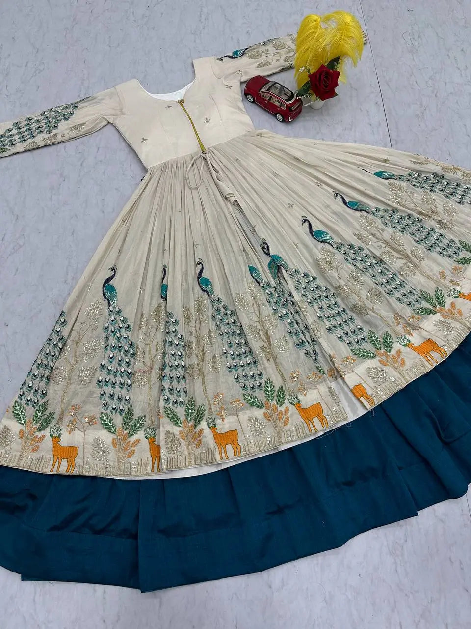 Traditional embroidered dress with peacock patterns on a plain background