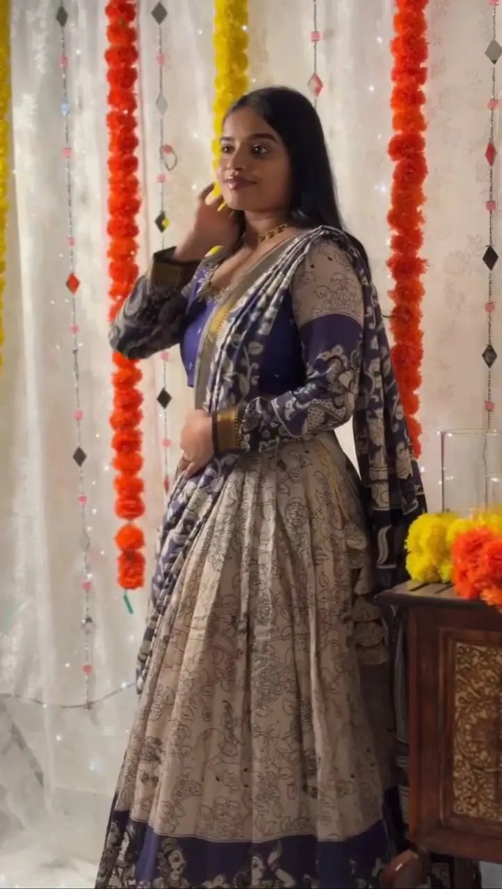 Woman in traditional attire standing in front of a decorative curtain with flowers.