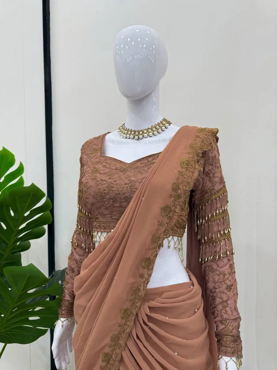 Elegant brown ethnic saree with gold embroidery and beadwork, styled on mannequin for festive occasions