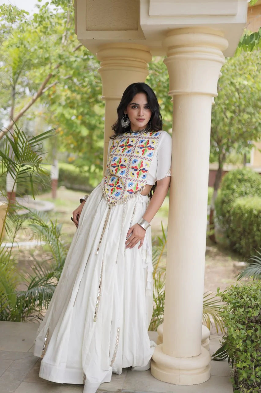 White chaniya choli with Kutchi mirror crop blouse and cowrie tassels, standing view