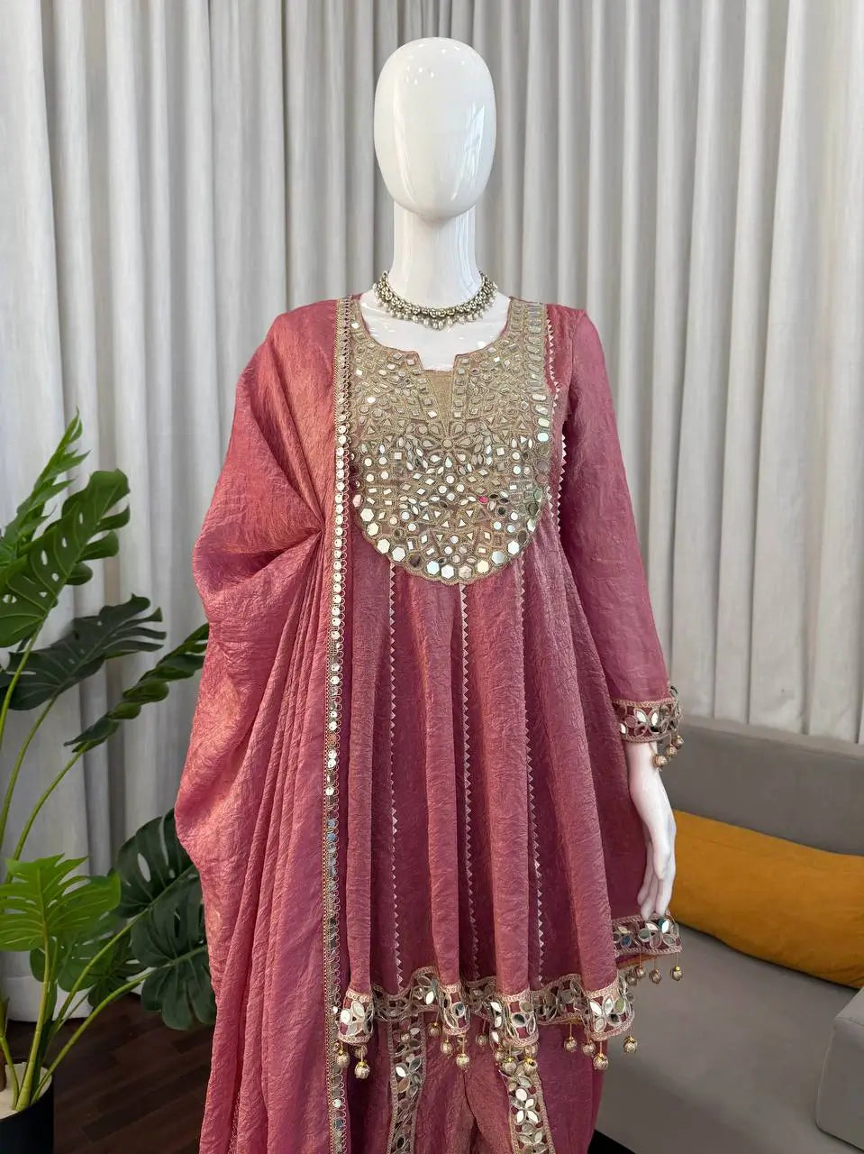 Pink ethnic Anarkali gown with mirror work, gold embroidery, and tassels for festive occasions