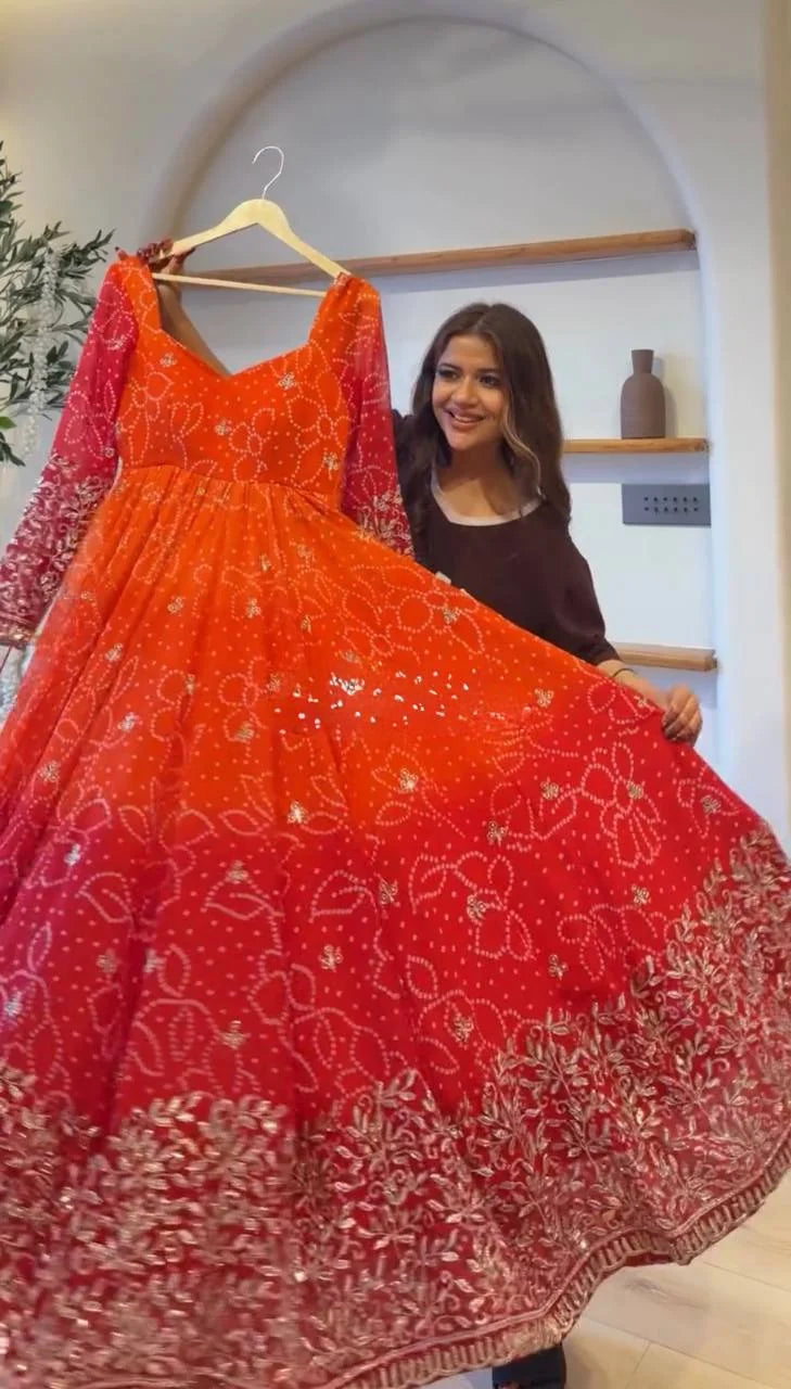 Red bandhani anarkali gown held showing red orange ombre print and sequin hem