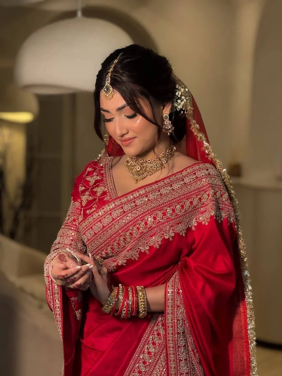 Red satin bridal saree close-up showing heavy gold codding and sequin embroidery