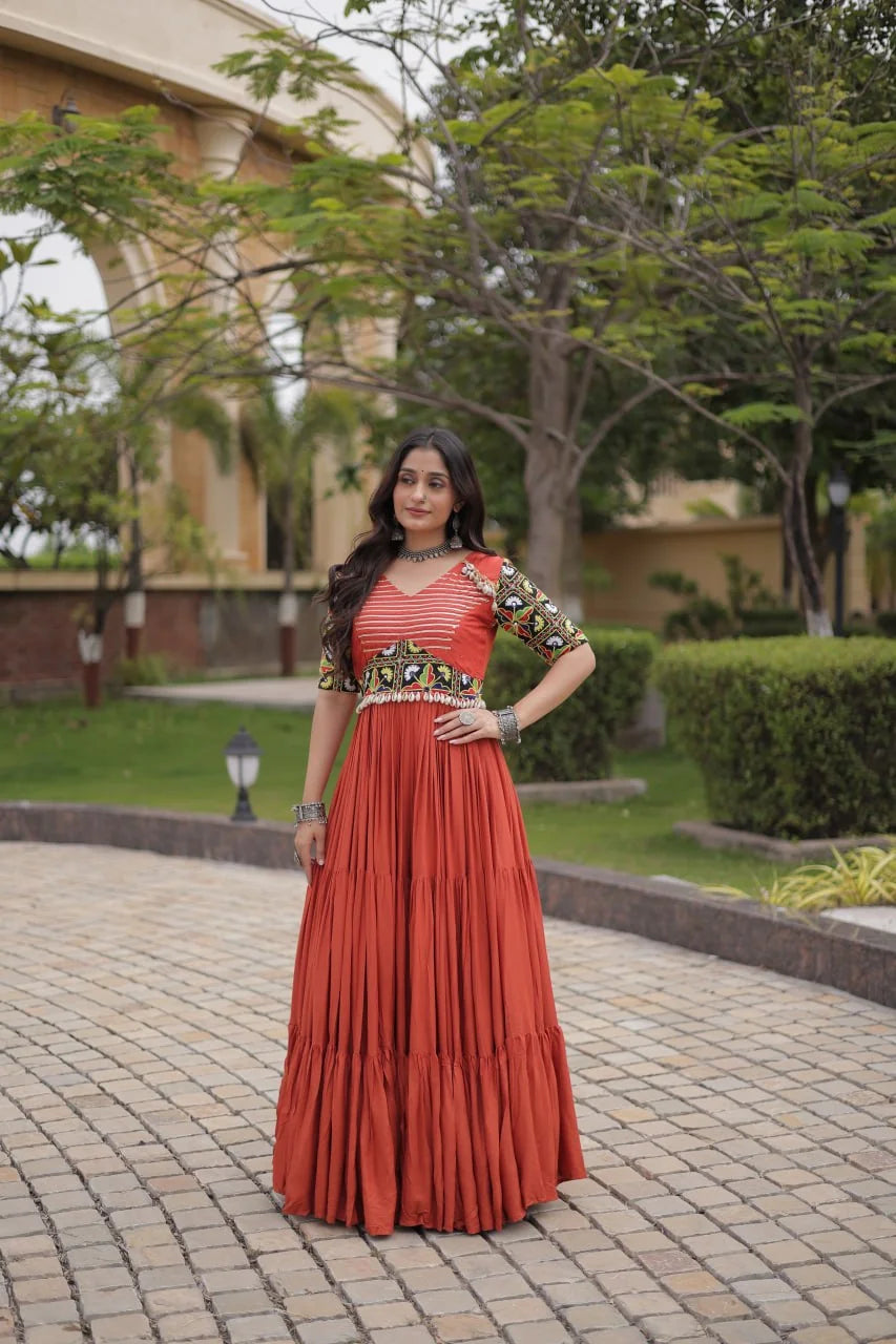 Rust navratri gown with gota-stripe bodice and cowrie waist belt, standing view